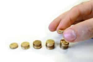 Money manager hand placing gold coins in stacks