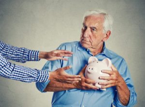 elderly man holding piggy bank to avoid elder abuse cases